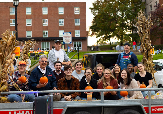Students sit in a group, holding their pumpkins, during the fall carnival on campus.