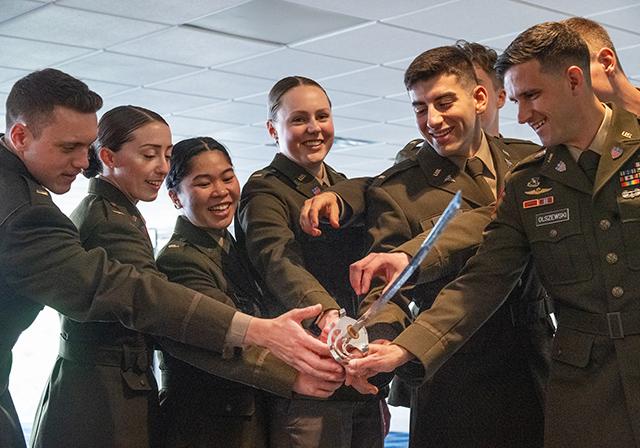 Elizabeth Osterhaus (center) holding a sword with her fellow cadets at the 2024 ROTC Commission Ceremony