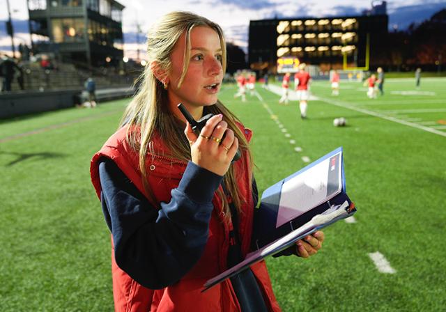 Business student Kacie Garofalo works on the sidelines during a Duquesne football game at Rooney Field
