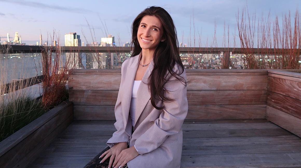 Duquesne alum Giovanna Elo sits on a rooftop deck overlooking the Manhattan skyline