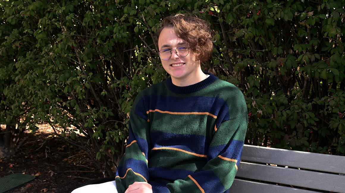 Student Jackson Cant sits on a bench outside of College Hall