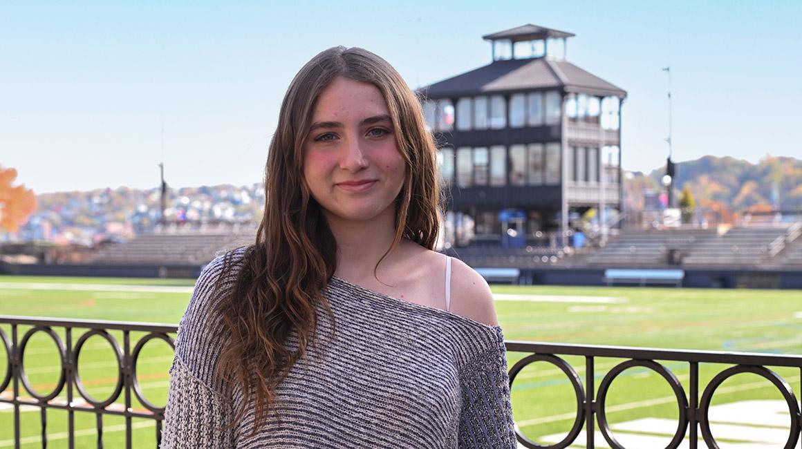 Viv Kuliecza stands in front of Rooney Field on Duquesne's campus