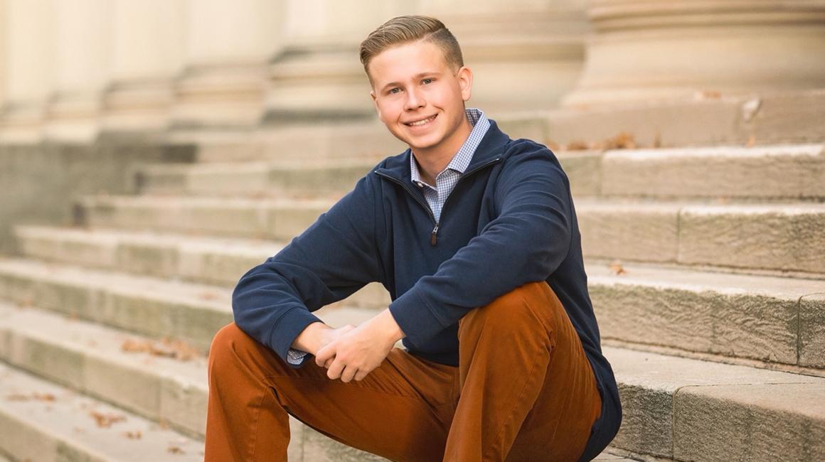 Student Xander Hill sits on steps outdoors