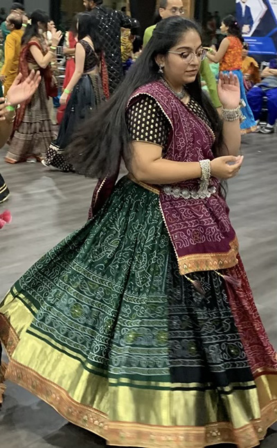 Hetanshi performs a traditional dance wearing a long green and gold dress