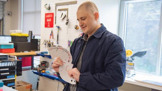 Luke Poljak demonstrates his cardistry skills by fanning out a deck of cards.