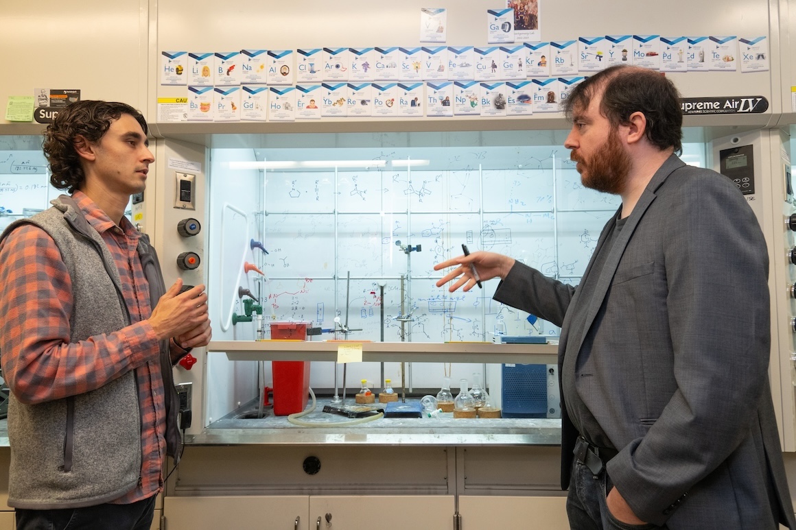 Professor speaking with student in front of white board