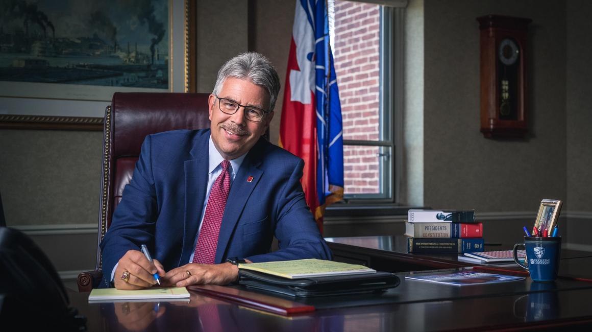 Ken Gormley sitting at his desk with a pen and paper pad.