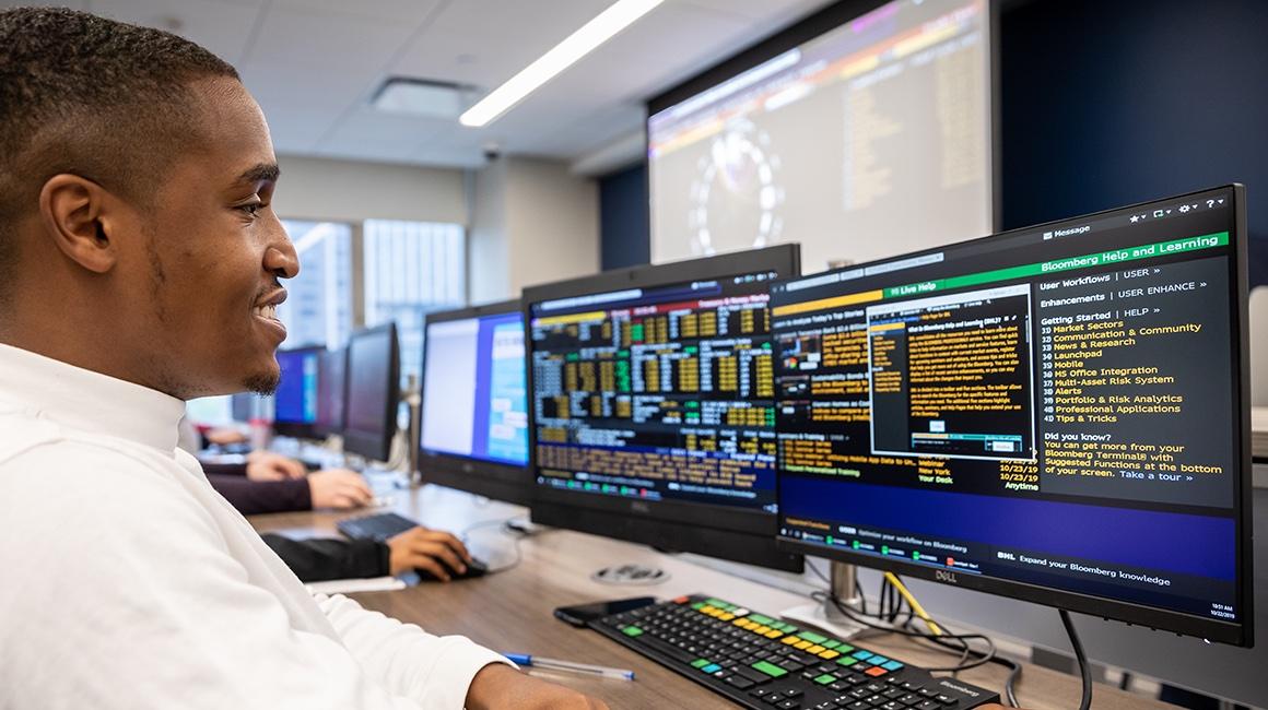 A Duquesne Business School student sits in front of a computer screen studying financial information