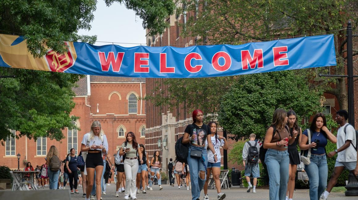 students walking under Welcome banner