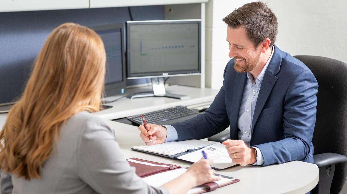 School of Business graduate student collaborates with a staff member at a desk