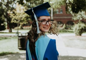 Edisa Music photographed in her graduation cap and gown on Duquesne's campu