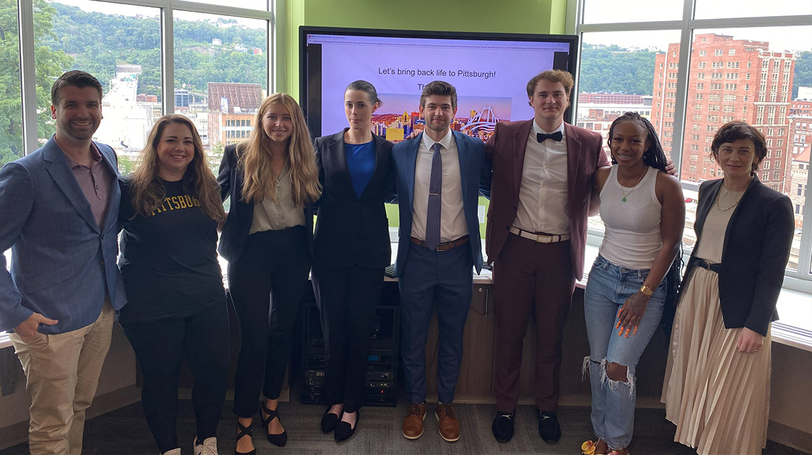 One-Year MBA students gather near windows after giving a presentation