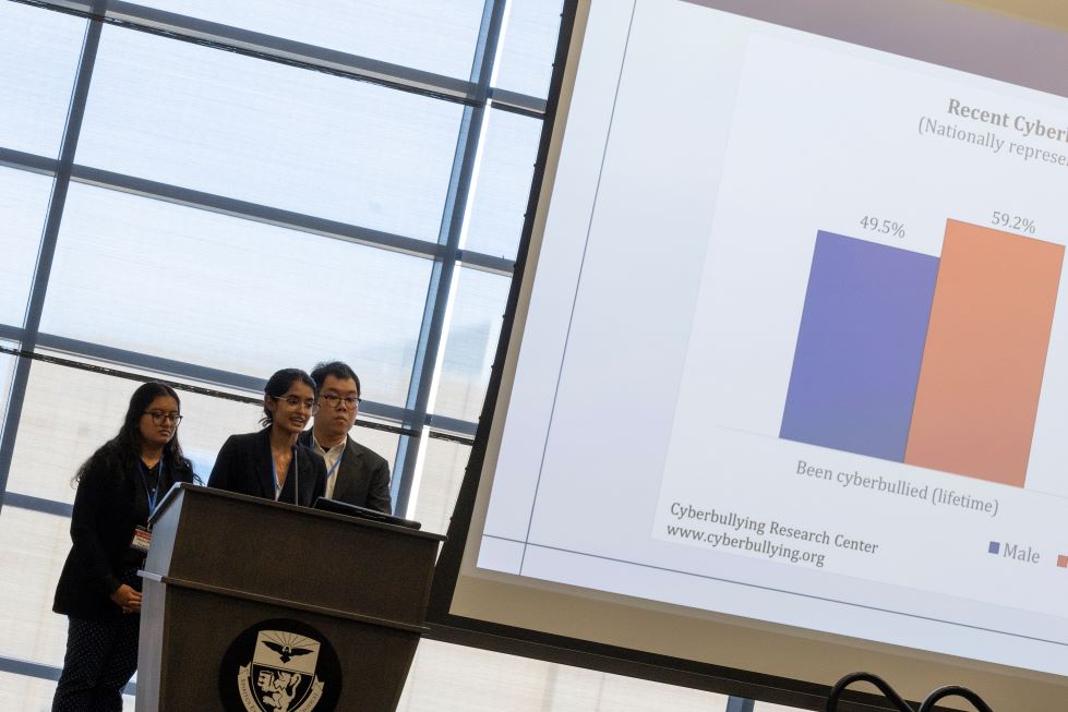 Three students presenting at lectern