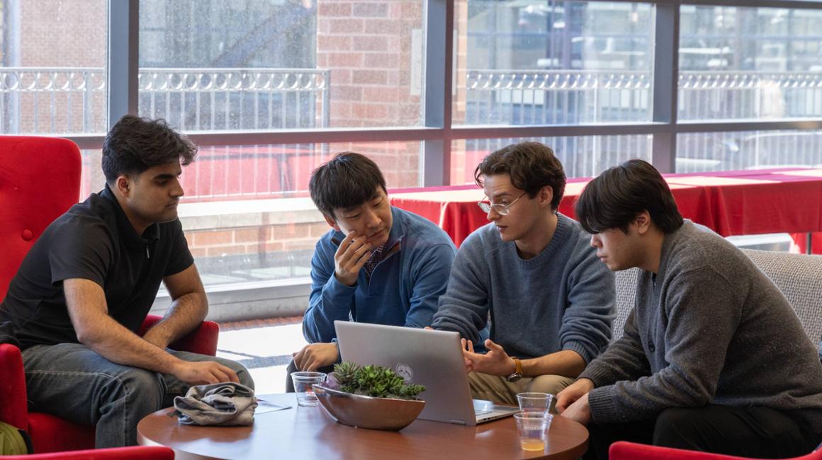 four team members sit together and put the finishing touches on their hackathon presentation