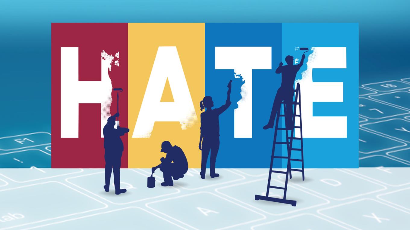 Human figures paint over the word hate