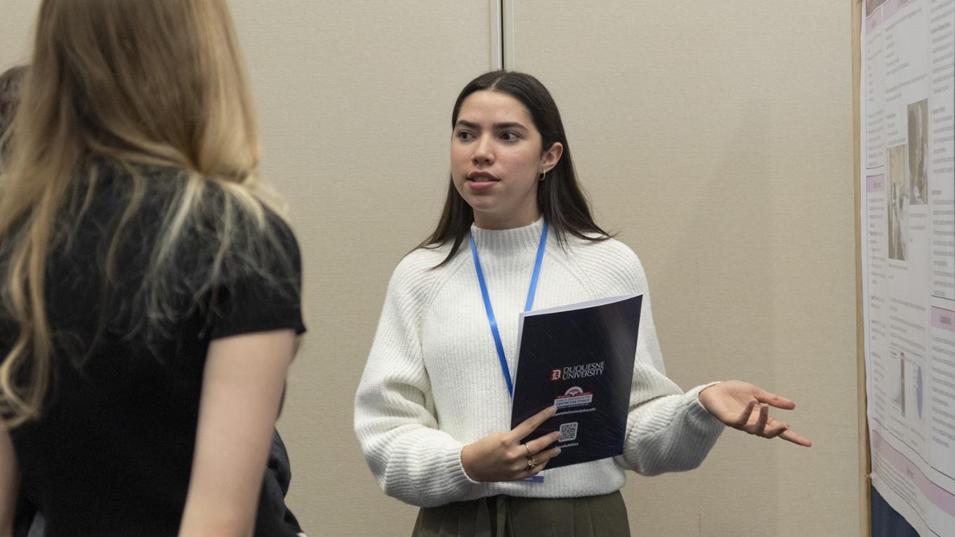 Student discusses poster with attendees of the 2024 Tech Ethics Symposium