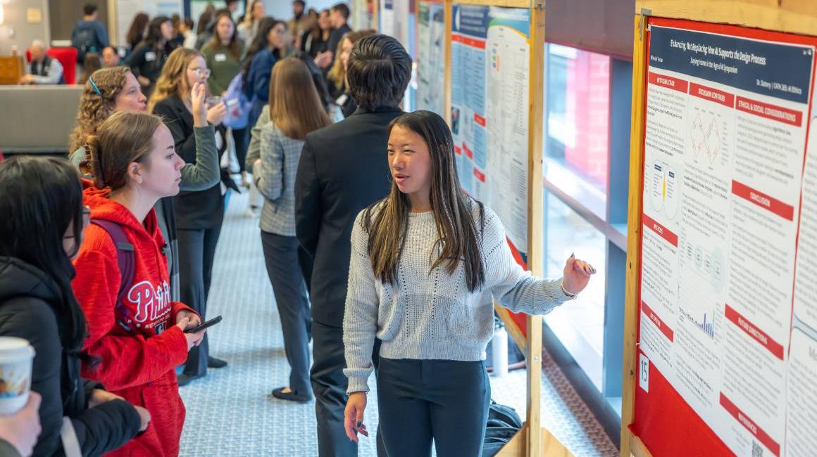 Student presenters and attendees discuss research posters