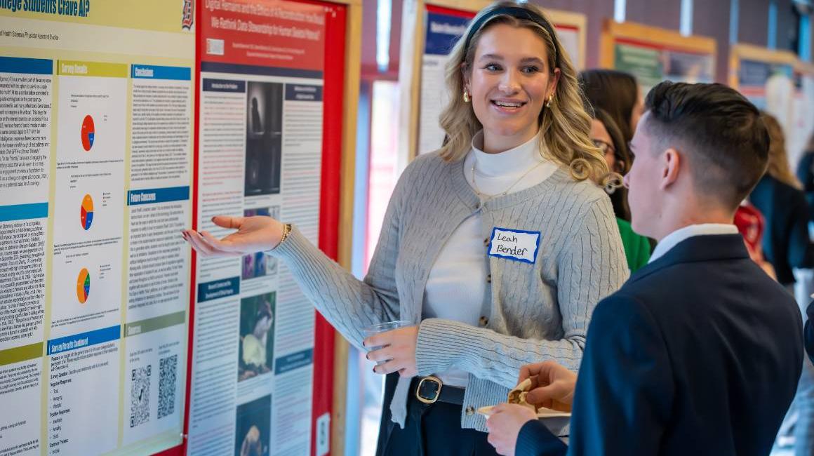 Student presents their research poster to another student at the 2025 Tech Ethics Symposium.