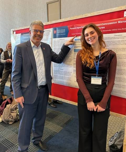 President Gormley standing with a female student in front of her poster presentation.
