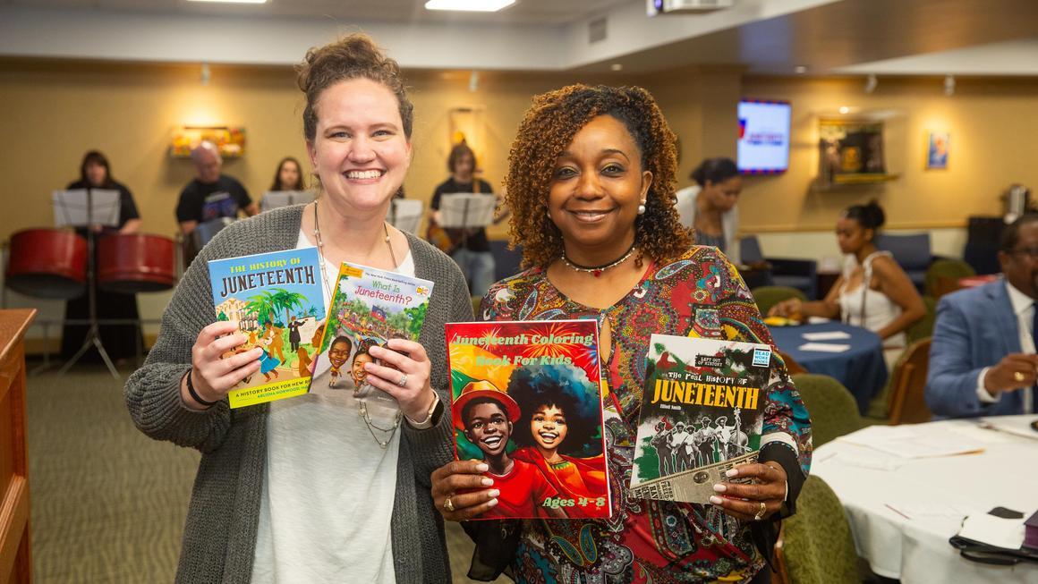 Duquesne staff Jen Smith and Vicki Bush holding Juneteenth books at the Juneteenth 2025 event