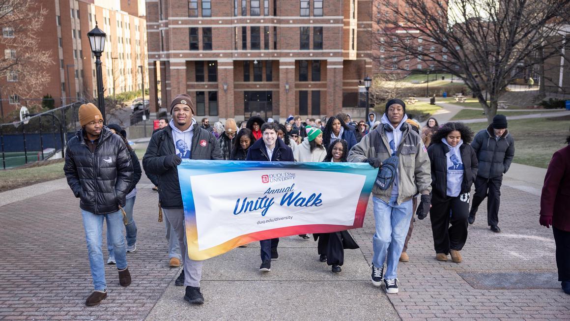 MLK Unity Walk 2026 participants walking up the hill with Vickroy Hall in the background