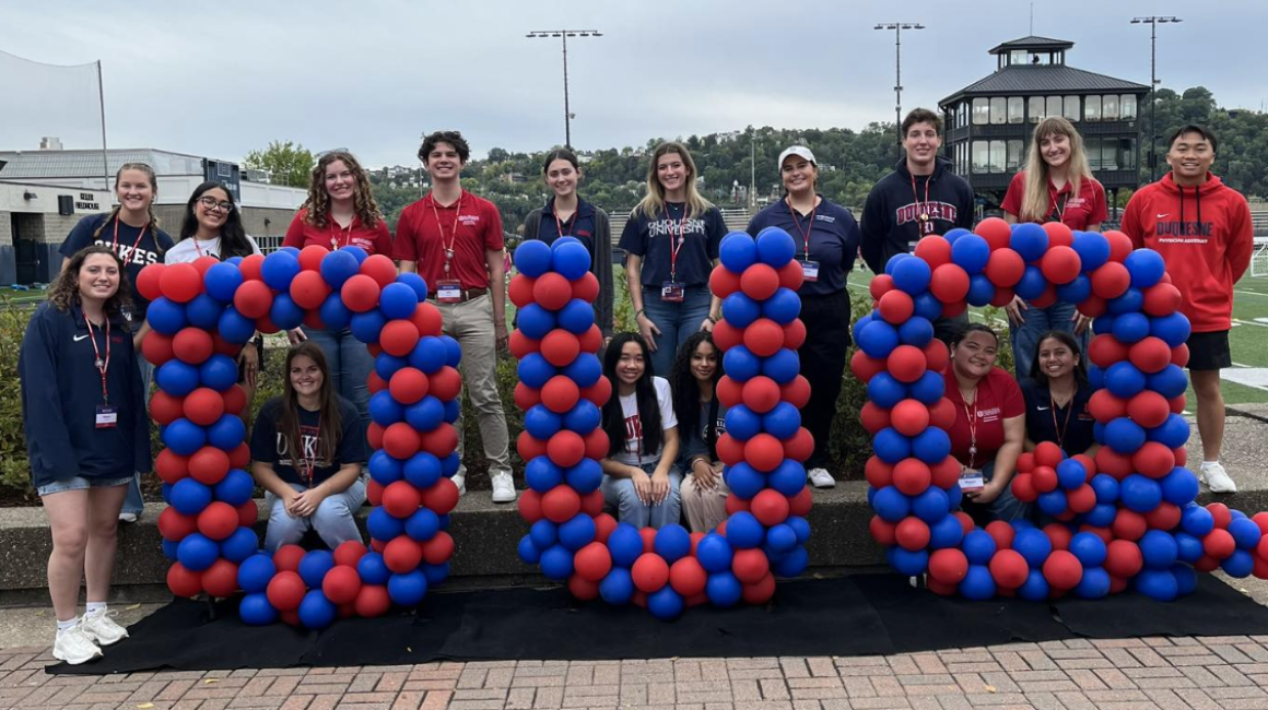 Red and blue baloons spelling DUQ with students smiling