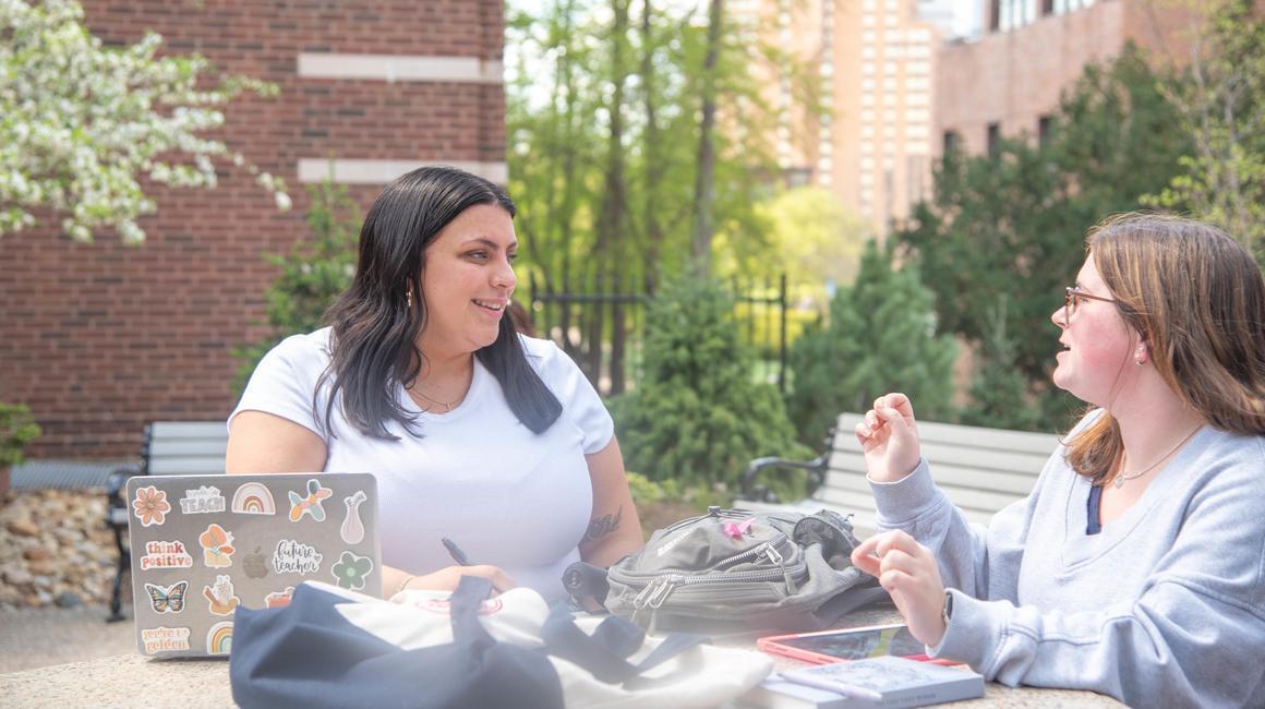 Students engaged in discussion while studying outside on campus.