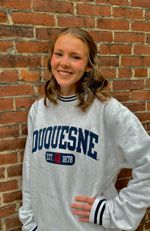 B.S.Ed. Early Childhood Education student and Excellence in Leading Teacher Program awardee Daniella Manchester wearing a Duquesne sweatshirt against background of brick wall